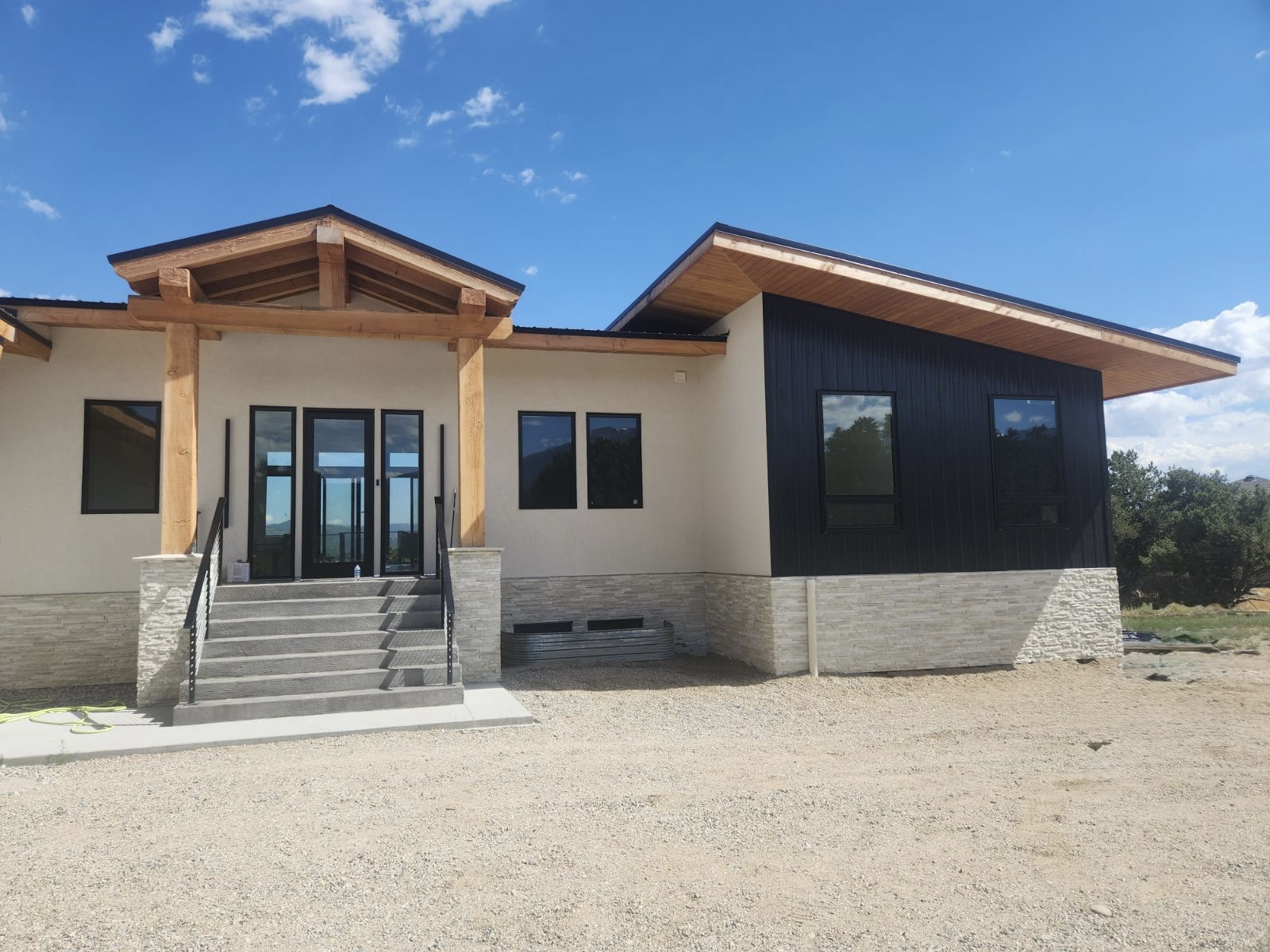 Custom modern mountain home with timber gable entry and dark metal siding
