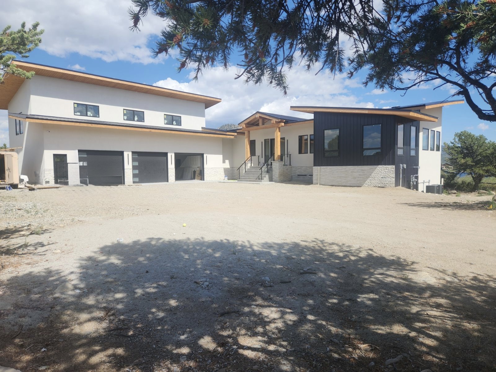 Finished custom home exterior with stucco, dark siding and timber beams